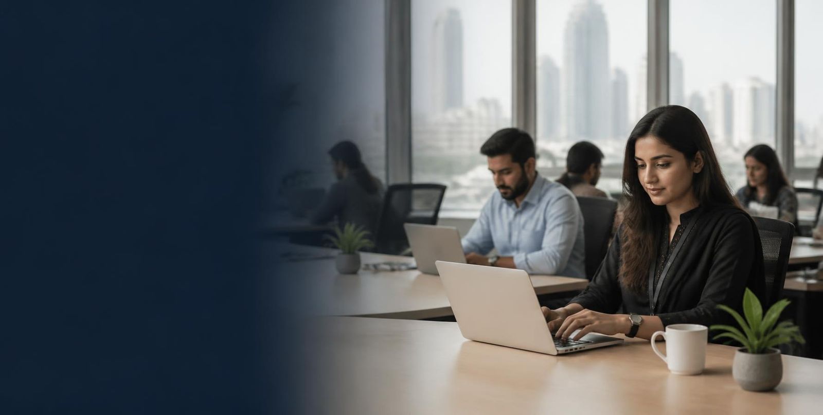 Pakistani professionals working on laptops in a bright, modern managed office with a city skyline view